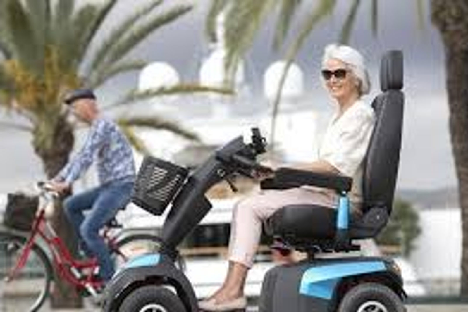 Pareja mayor paseando en scooter eléctrico junto al mar